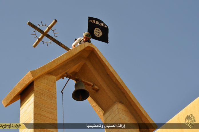 Ein IS-Terrorist ersetzt das Kreuz mit der IS-Flagge über dem St. Georgskloster bei Mosul, Irak. Foto Gates of Nineveh