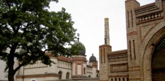 Links im Hintergrund die Synagoge von Halle; im Vordergrund der Eingang zum jüdischen Friedhof. Foto Allexkoch, CC BY-SA 4.0, https://commons.wikimedia.org/w/index.php?curid=42881121