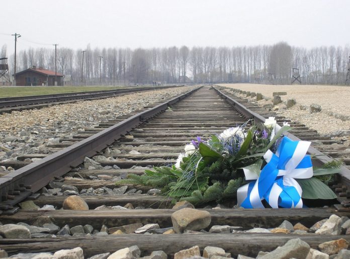 Blumen zum Gedenken auf den Bahngleisen der Entladerampe im KZ Auschwitz-Birkenau. Foto Dnalor 01, CC BY-SA 3.0 at, https://commons.wikimedia.org/w/index.php?curid=33103769