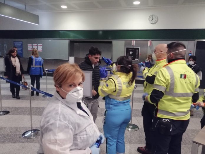 Freiwillige Helfer des Katastrophenschutzes bei der Gesundheitskontrolle am Flughafen 
