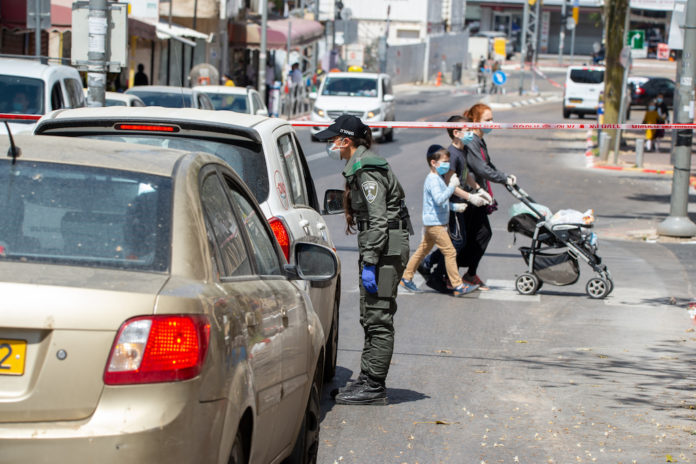 Grenzschutzpolizistin die in der Stadt Bnei Brak vorbeifahrende Autofahrer kontrolliert und die Mobilitätsbeschränkungen durchsetzt. 3. April 2020. Foto Kobi Richter/TPS