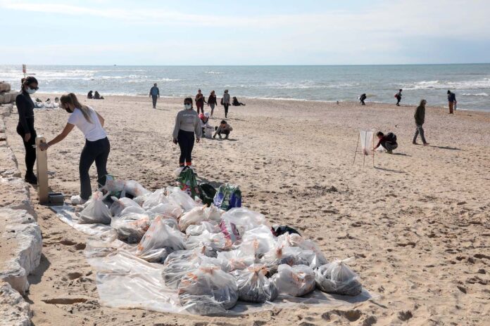 Freiwillige säubern den Strand in Tel Aviv von Teer, nachdem ein Schiff im Mittelmeer Öl freigesetzt und damit einen Grossteil der israelischen Küste verschmutzt hat. 20. Februar 2021. Foto Gideon Markowicz/TPS
