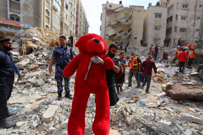 Ein Mann in Gaza trägt einen perfekt sauberen, riesigen roten Stoffteddybär. Laut verschiedenen Medien (z.Bsp. Basler Zeitung 17. Mai 2021) soll der Teddybär aus den Trümmern eines eingestürzten Hauses stammen. Foto IMAGO / ZUMA Wire