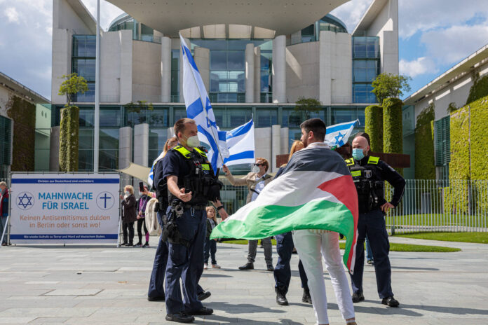 Mahnwache für Israel vor dem Bundeskanzleramt Deutschland, Berlin am 19.05.2021. Polizei spricht mit Gegendemonstrant. Foto IMAGO / Achille Abboud