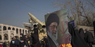 Eine verschleierte iranische Frau hält ein Porträt von Irans Oberstem Führer Ayatollah Ali Khamenei, hinter ihr die iranische strassengängige einstufige Feststoffrakete Zolfaghar Basir (oben) und die ballistische Mittelstreckenrakete Dezful an einer Militärausstellung. Foto IMAGO / NurPhoto