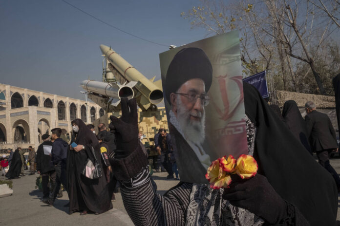 Eine verschleierte iranische Frau hält ein Porträt von Irans Oberstem Führer Ayatollah Ali Khamenei, hinter ihr die iranische strassengängige einstufige Feststoffrakete Zolfaghar Basir (oben) und die ballistische Mittelstreckenrakete Dezful an einer Militärausstellung. Foto IMAGO / NurPhoto