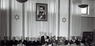 David Ben-Gurion beim Verlesen der Unabhängigkeitserklärungin Tel Aviv. Über ihm das Porträt von Theodor Herzl, dessen Vision eines eigenen Staates für das jüdische Volk rund 50 Jahre später Wirklichkeit wurde. Foto Government Press Office, Israel (GPO)