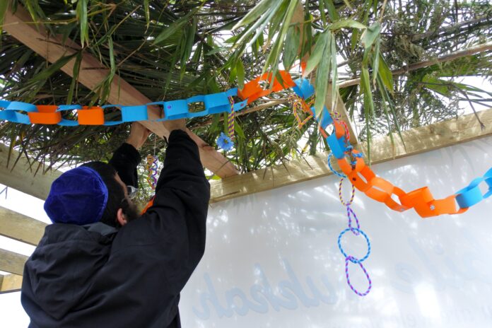 Symbolbild. Mann schmückt eine Sukka an Sukkot. Foto IMAGO / Pond5 Images