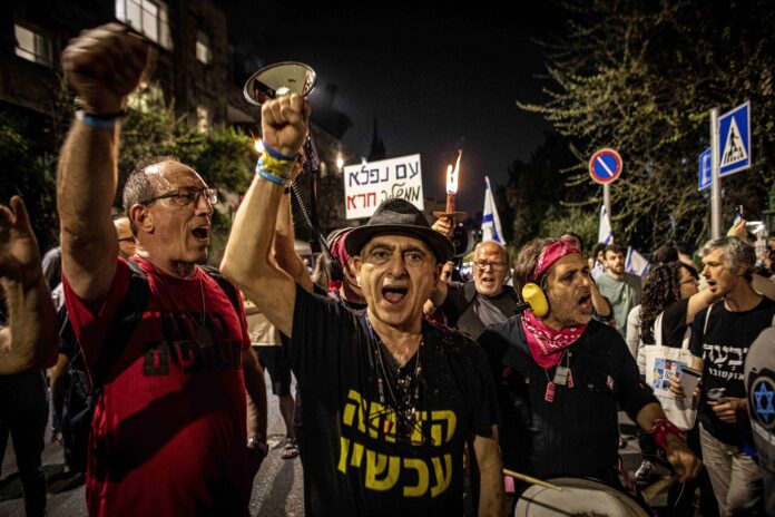 Während einer Demonstration schwenken Demonstranten ein Plakat mit der hebräischen Aufschrift 