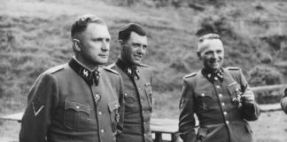 Josef Mengele (Mitte) zwischen den Kommandanten Richard Baer (links) und Rudolf Höß an der Solahütte bei Auschwitz, 1944. Aufnahme aus dem Auschwitz-Album Karl-Friedrich Höckers. Foto USHMM, Gemeinfrei, https://commons.wikimedia.org/w/index.php?curid=65081325